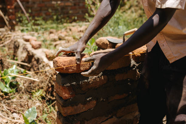 istock Man building a brick wall in Uganda, Africa 1302008723