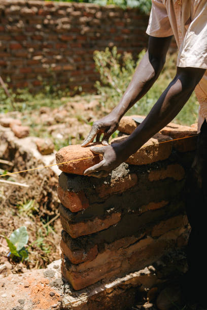 istock Man building a brick wall in Uganda, Africa 1302008724