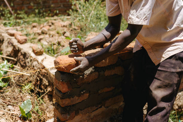 istock Man building a brick wall in Uganda, Africa 1302008736