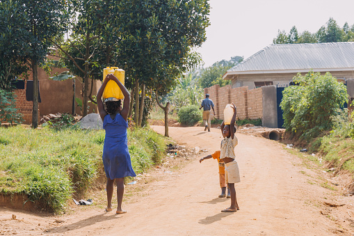 Mother and child carrying water home from a well in Entebbe, Uganda