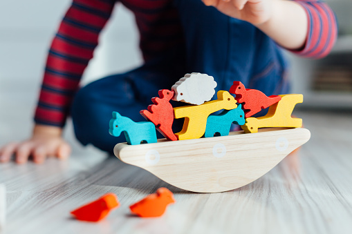 Close up of little boy playing with wooden colorful toys.