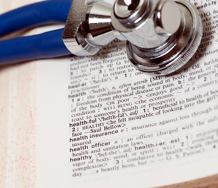 close view, no people, 1 stethoscope on 1 dictionary, partial view of stethoscope, partial view of dictionary