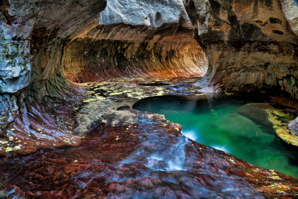 Green pool, flowing water and a circular rock formation at the Subway, a unique tunnel scuplted by the Left Fork of North Creek in Zion National Park, Utah