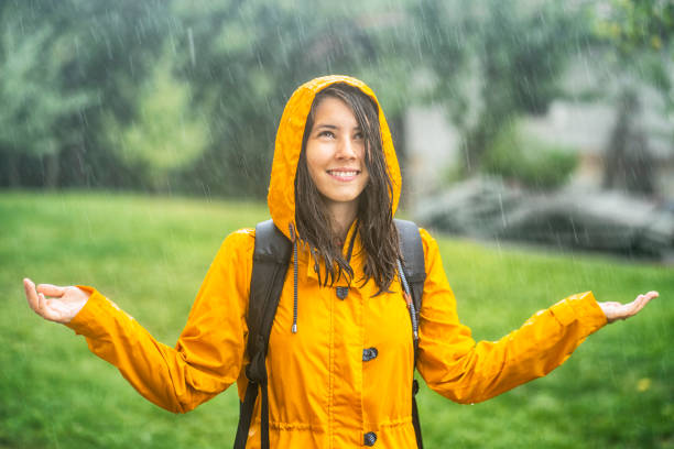 junges mädchen mit spaß unter dem regen - drenched raincoat rain clothing stock-fotos und bilder