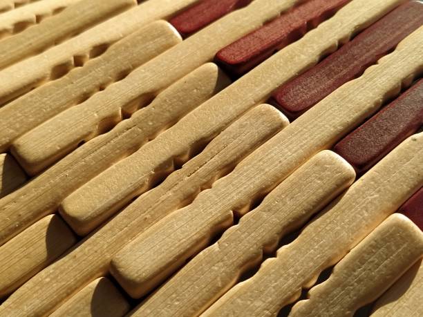 reed or wood mat. The rug is a mat under the hot. Knitted processed wood sticks with rounded edges. Close-up. Yellow, brown and beige colors. Side lighting. Traditional bamboo pad texture. caña o estera de madera. la alfombra es una estera bajo el calor. palos de madera procesada de punto con bordes redondeados. primer plano. colores amarillo, marrón y beige. iluminación lateral. textura tradicional de almohadilla de bambú