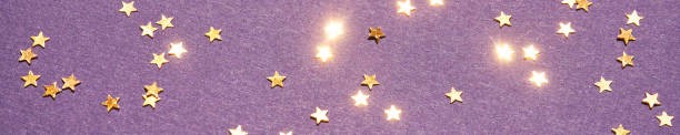 Gold stars on purple background. Yellow glitter backdrop. Golden texture