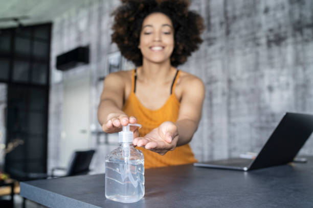 istock Afro American woman disinfecting her hands while working in office 1302017780