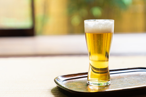 A refreshing pint of cold beer on a wood surface with white background.