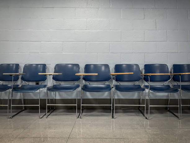 istock A Line of Blue Empty School Chairs Lined-Up Against a Brick Wall in an Empty Room 1302023980