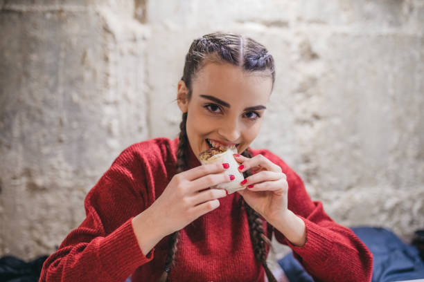 istock Cheerful woman eating a chicken wrap 1302026103