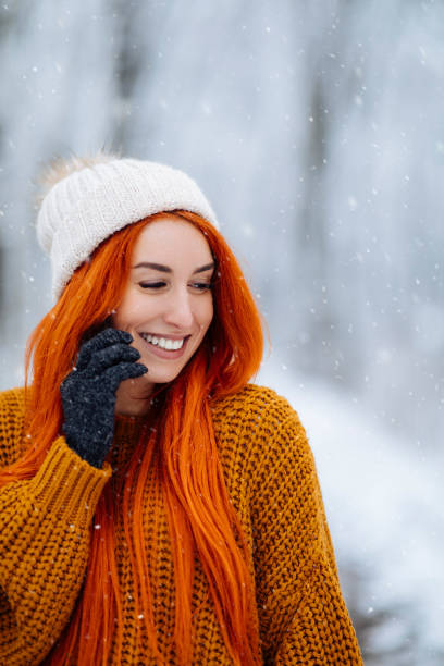 Sign me up for winter anyway of the year Young red haired woman talking on her cellphone while taking a walk in the snow anyway stock pictures, royalty-free photos & images