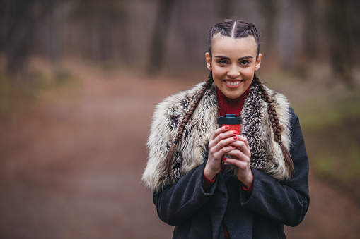 Portrait of a beautiful young woman holding a thermos