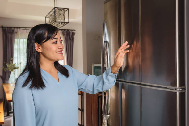 istock Asian mature woman using smart refrigerator or UX interface(Blank Smart Fridge) in the kitchen at home, Smart future home and Internet of Things concept 1302044787