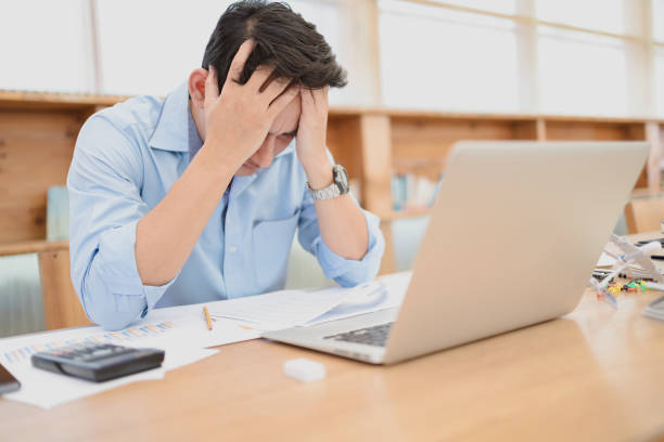 istock Tired businessman at workplace in office holding his headache or angry. Overworking, making mistake, stress, termination, fail, bad, sad tired or depression concept 1302047600