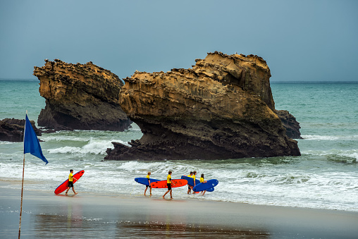 Surfer on a rainy summerday with their colorful surfboards on the beach of Biarritz 13.08.2018