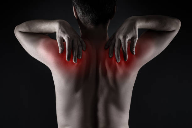 Shoulder blades pain, man with backache on black background Shoulder blades pain, man with backache on black background, painful area highlighted in red unusual muscle pain stock pictures, royalty-free photos & images