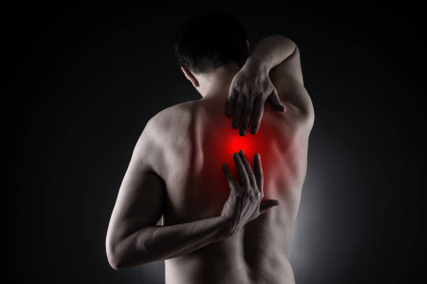 Pain between the shoulder blades, man suffering from backache on black background Pain between the shoulder blades, man suffering from backache on black background, painful area highlighted in red scapula stock pictures, royalty-free photos & images