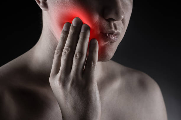 Man suffering from a toothache on black background, dentistry and periodontal disease concept Man suffering from a toothache on black background, dentistry and periodontal disease concept, painful area highlighted in red abscess stock pictures, royalty-free photos & images