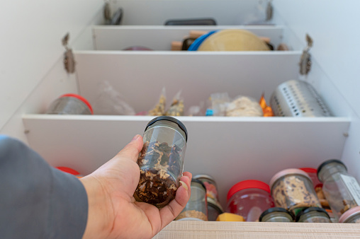 low angle view human hand holding a bottle of raw food from kitchen pantry cabinet shelf