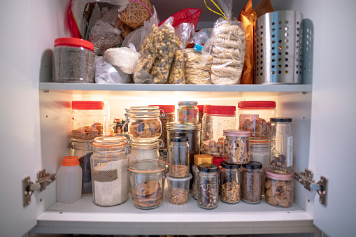 cabinet closet full of bottle of dried food, preserved food, biscuits , nuts, snack, candy, raw food, flour, cereal