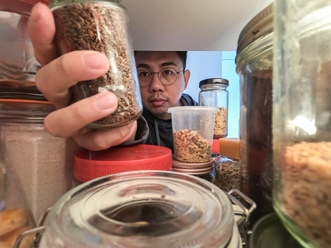 point of view asian chinese male retrieving food bottle from shelf cabinet at kitchen