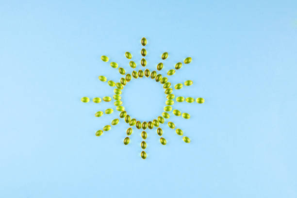 광선이 있는 태양의 형태로 비타민 d3를 함유한 노란색 캡슐. 건강하고 의료적인 컨셉, 햇빛 비타민. - vitamin d capsule fish oil yellow 뉴스 사진 이미지