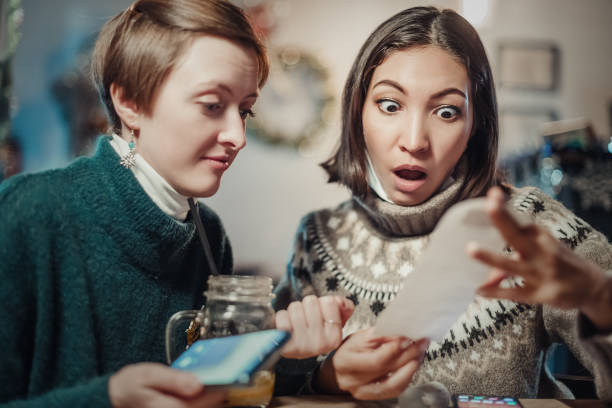 asian woman stares at the check for dinner at the restaurant, her eyes bulging. the concept of inflation and devaluation of money and reduction of purchasing power of the population. - number 33 fotos imagens e fotografias de stock