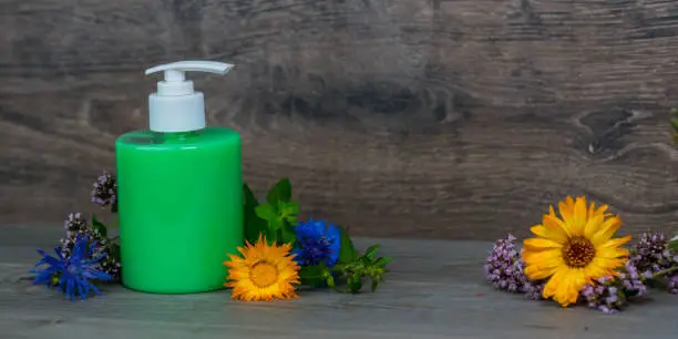 green organic liquid soap in plastic dispenser with fresh herbs