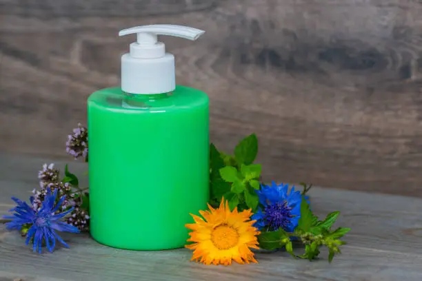 green organic liquid soap in plastic dispenser with fresh herbs