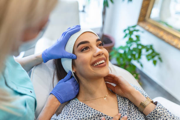 massaggiatore che dà trattamento alla bella bruna. primo piano, ritratto di una giovane bella ragazza, con la pelle impeccabile, che il massaggiatore maestro fa massaggio facciale, in guanti medici. in un salone di bellezza - massaging facial massage beautician beauty treatment foto e immagini stock