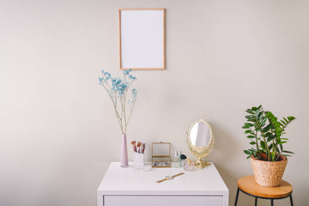 istock Minimalistic female still life workplace composition pastel colors. White table, empty poster mock up frame, stylish fashion accessories golden mirror. Home plant in eco wicker flower pot. Template. 1302064643