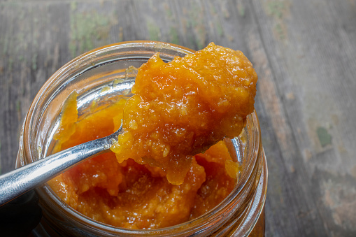 Spoon Full of Fresh Domestic Orange Marmalade Over Opened Jar. Natural Juicy . Peels Also Inside.