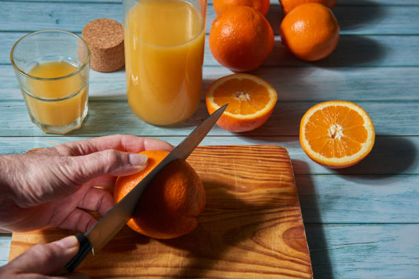 istock A man's hand slicing oranges to extract their juice. 1302067526