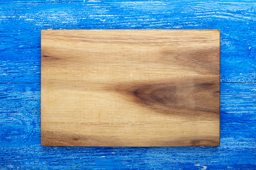 Empty rectangular cutting board on a blue wooden table. Space for text. Top view.