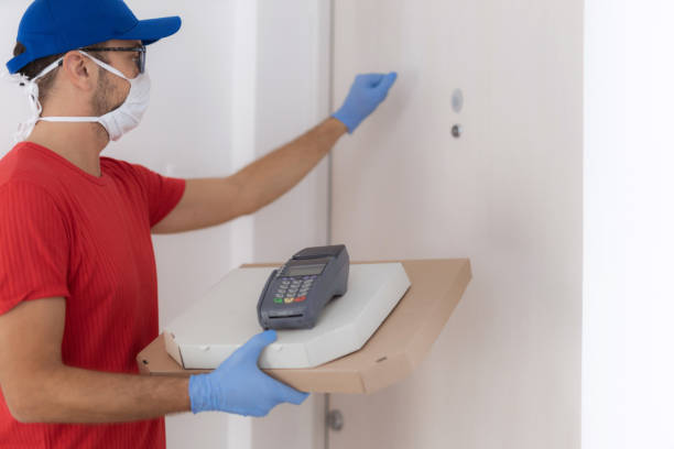 istock Delivery guy with protective mask holding pizza box at the door. 1302068627