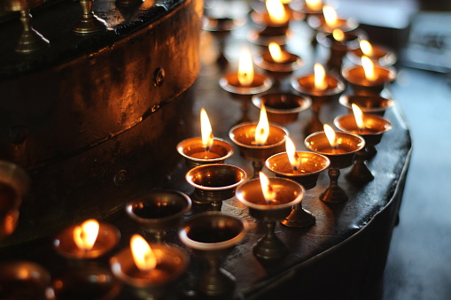 Velas budistas de altar en el Festival religioso de lámparas de mantequilla vieja en templos y monasterios. Hermosa vista escénica tranquila de lámparas de aceite y llama balanceada para orar en recipiente metálico photo