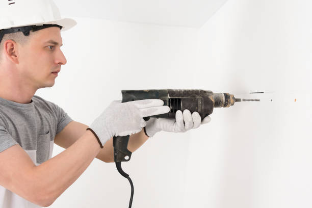 istock a worker in a helmet makes a hole in a concrete wall with a puncher 1302070118