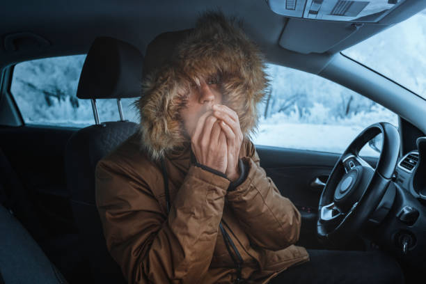 mann in daunenjacke versucht, sich warm zu halten und im winter nicht in seinem stehengebliebenen auto zu frieren. das konzept eines gefährlichen unfalls oder eines heizungsausfalls in der kalten jahreszeit - blizzard ice damaged snow stock-fotos und bilder