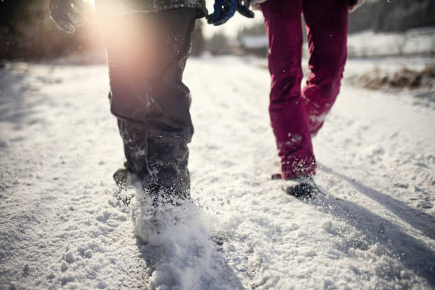 Two kids are walking on a snow covered road on sunny winter day.\nShot with Canon R5.