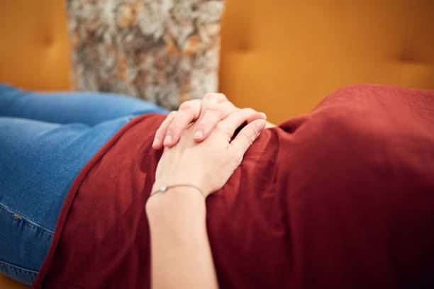 istock Woman with stomach problems lying at home on a couch. 1302071943