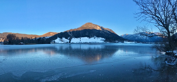 Schliersee in winter at sunset. Upper Bavaria is freezing. The snow-capped peaks of the Alps turned bright pink and red.