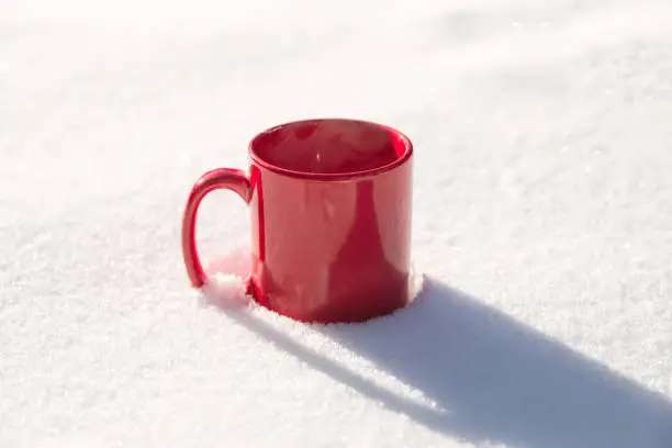 Steaming cup of hot coffee,tea or chocolatemilk in the cold fresh white snow, Winter,cozy,drink,snowy day concept background in nature beauty Copy space