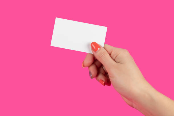istock Hand holding paper business card on pink background 1302077096
