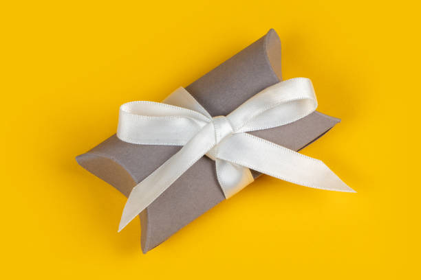 istock Gray gift box with silver ribbon on yellow background 1302077143