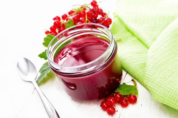 istock Jam of red currant in jar on light wooden board 1302077308