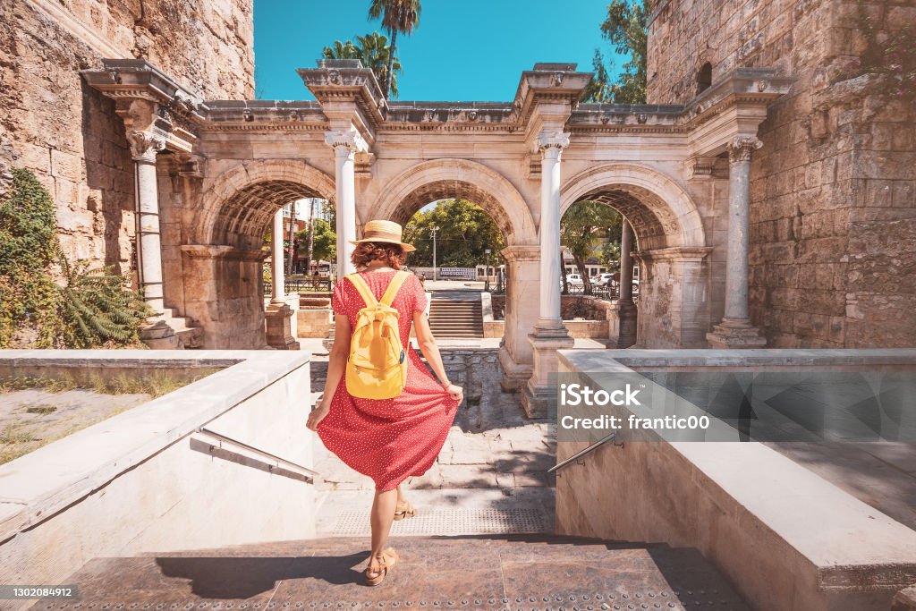 Happy female tourist traveler discover interesting places and popular attractions and walks in the old city of Antalya, Turkey. The famous Roman gate of Hadrian Antalya City Stock Photo