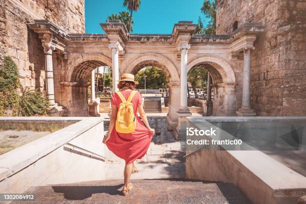Happy Female Tourist Traveler Discover Interesting Places And Popular Attractions And Walks In The Old City Of Antalya Turkey The Famous Roman Gate Of Hadrian Stock Photo - Download Image Now
