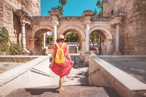 happy female tourist traveler discover interesting places and popular attractions and walks in the old city of antalya, turkey. the famous roman gate of hadrian - província de antália imagens e fotografias de stock