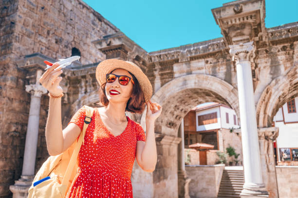 traveler with a toy plane on the background of the archaeological monument - the gate of the emperor hadrian in the old city of antalya. concept of air tickets and airlines in turkey - turkey tourist ephesus roman imagens e fotografias de stock