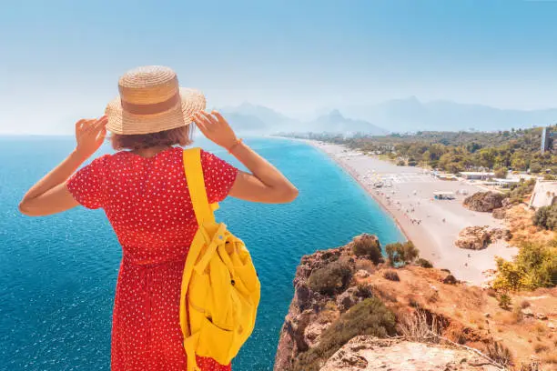 Photo of Happy female tourist looking from the height of the observation viewpoint overlooking Konyaalti beach in Antalya. Tourism and lifestyle in Turkey